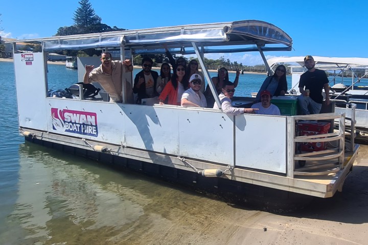 Group of people on a docked boat at a sunny waterfront.