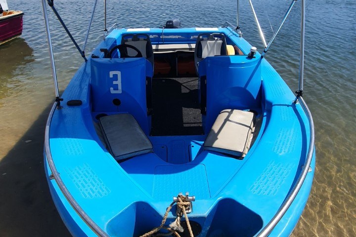a blue and white boat sitting next to a body of water