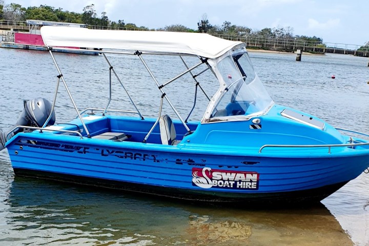 a blue and white boat sitting next to a body of water