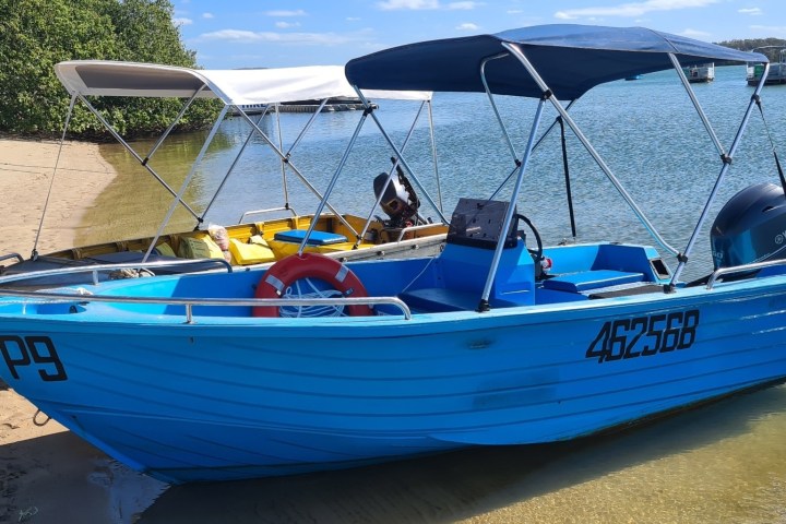 a blue and white boat sitting next to a body of water