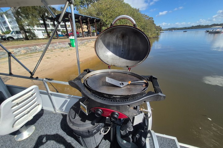 Open grill on boat near beach and water on a sunny day.