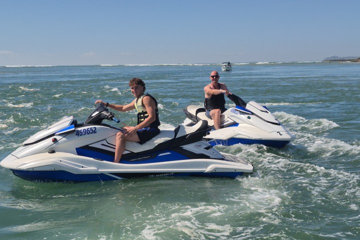 Two people riding jet skis on the ocean.