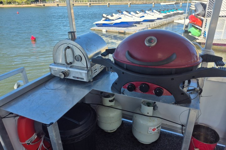 Two grills on a boat with water and jet skis in the background.