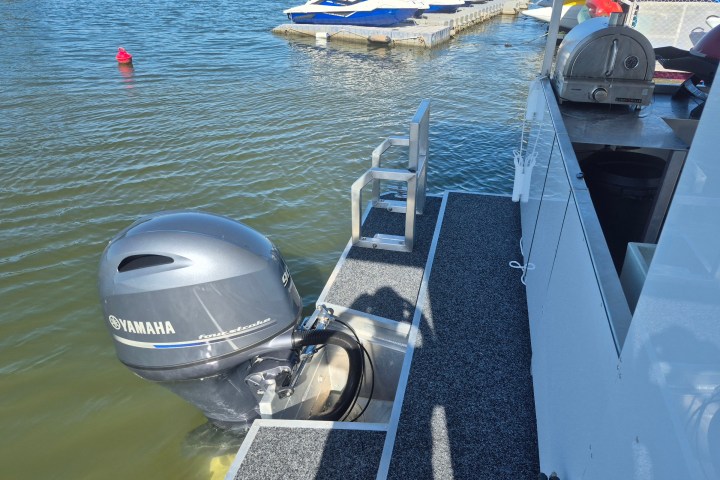 Boat deck with a Yamaha outboard motor, near a dock with jet skis.
