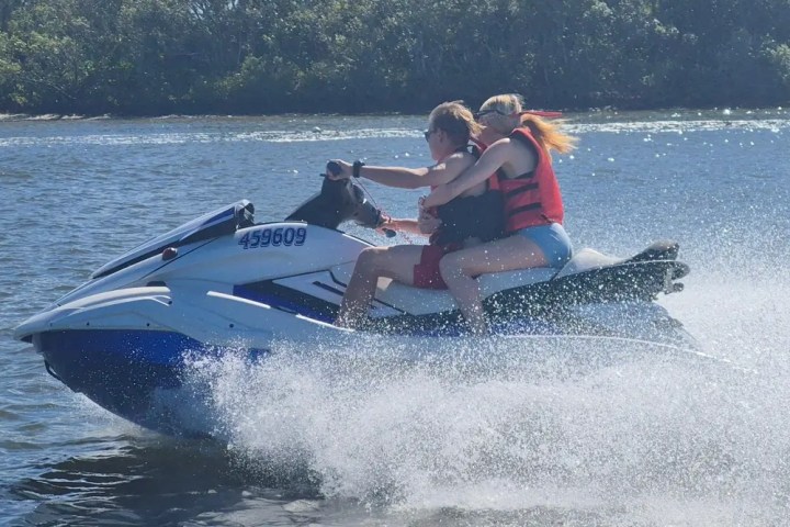 Two people riding a jet ski on a sunny day.